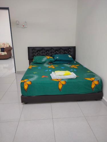 a bed with a green comforter with butterflies on it at Juliana Homestay in Jitra