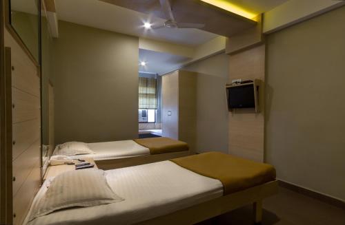 Cette chambre comprend 2 lits et une télévision. dans l'établissement Sandhya Residency, à Bangalore