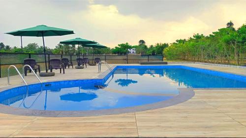 a swimming pool with chairs and umbrellas on a patio at VAMA Retreats in Bangalore