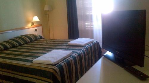 a hotel room with two beds and a television at Hotel Le Grazie in Portovenere