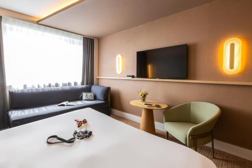 a hotel room with a bed and a couch and a tv at Novotel Nancy in Nancy