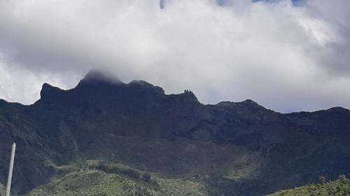 a mountain in the distance with a cloudy sky at LOCATIONS VERT EDEN in La Plaine des Cafres