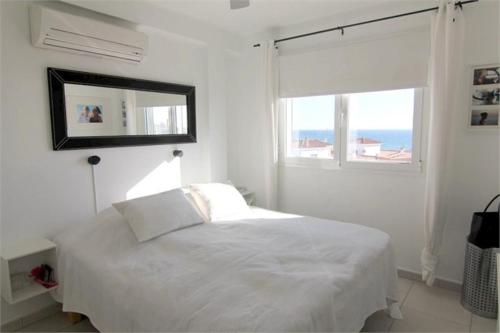 a white bedroom with a bed and a window at Casablanca in Nerja