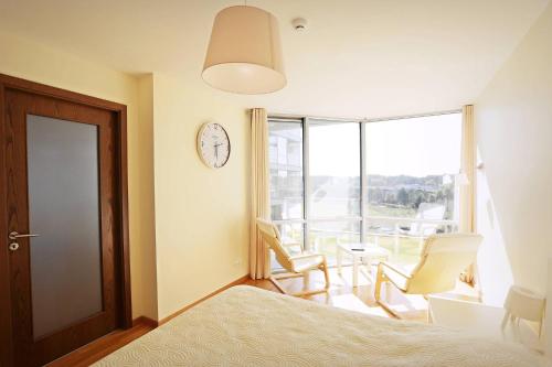 a bedroom with a bed and chairs and a clock at Elija in Šventoji