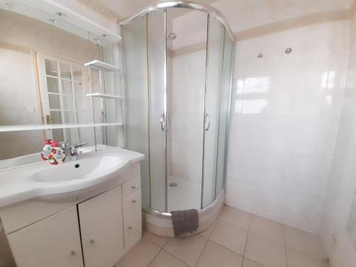 La salle de bains blanche est pourvue d'une douche et d'un lavabo. dans l'établissement Palais des Iles, à Cannes
