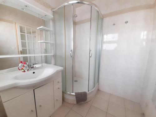 une salle de bain blanche avec une douche et un lavabo dans l'établissement Palais des Iles, à Cannes