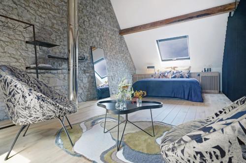 Maison Eliacé في Heure: غرفة نوم بسرير وطاولة وكراسي