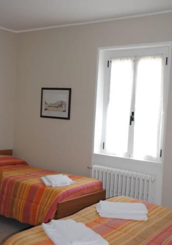 a bedroom with two beds and two windows at Albergo del mera-ristorante da Lui in Sorico