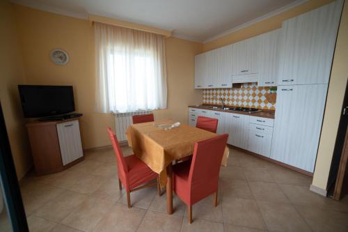 a kitchen with a dining table and red chairs at Villa Bella Vista in Santa Domenica