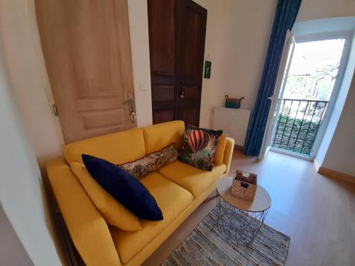 a living room with a yellow couch with pillows on it at Le gîte du Tarn in Aguessac