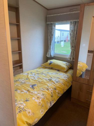 a small bedroom with a bed and a window at The Pearl - Deluxe Access Caravan in Skegness