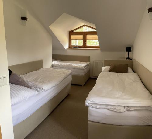 two beds in a small room with a window at Resort-Restaurant Stilec in Kamenný Újezd