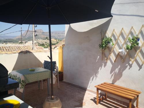 un patio con mesa, sombrilla y banco en Casa en el centro del pueblo de Finestrat, en Finestrat