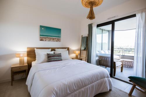 une chambre avec un grand lit blanc et un balcon dans l'établissement Appartement de luxe pour des vacances paisibles., à Porto-Vecchio