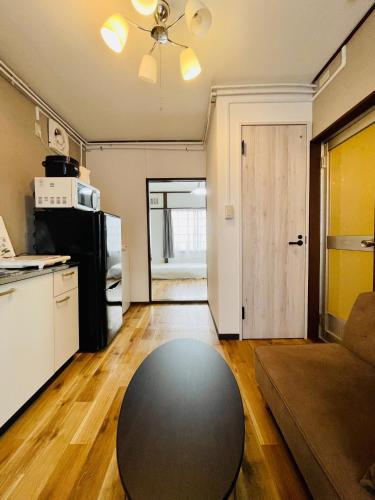 a living room with a black table and a kitchen at 観光や仕事に便利ｻｰﾋﾞｽｱﾊﾟｰﾄﾒﾝﾄ札幌さくら2-2小型犬滞在可能 in Toyohira