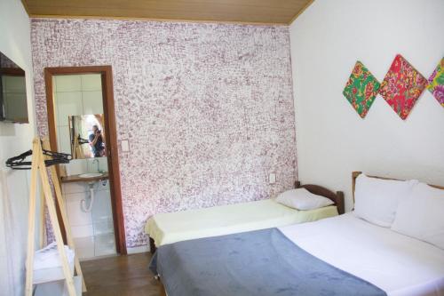 a bedroom with two beds and a wall with a mirror at Vila Flores Pousada in Serra do Cipo
