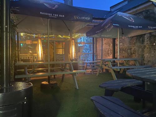 grupa stołów piknikowych i parasoli na patio w obiekcie The Bailey bar & lounge w mieście Athlone