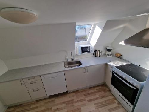 a small white kitchen with a sink and a stove at Ferielejlighed Skovby ved Bogense in Bogense