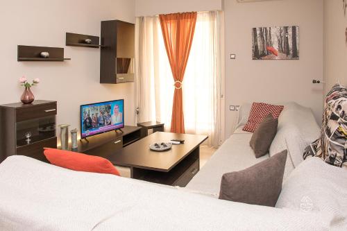 a living room with two white couches and a television at Alexandra's Apartment in Volos