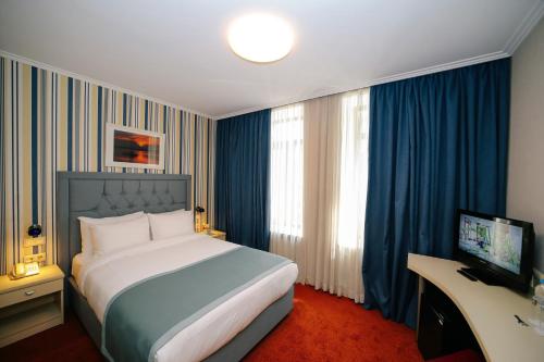 a bedroom with a large bed and a television at Sharden Villa Boutique Hotel in Tbilisi City