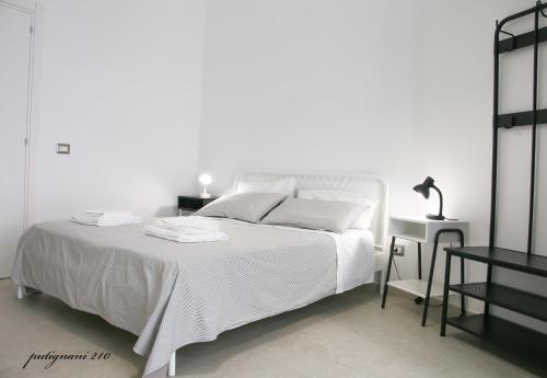 a white bedroom with a white bed and a table at Putignani 210 Apartment in Bari