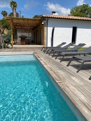 une maison avec une terrasse en bois et une piscine dans l'établissement Villa de charme avec piscine à Ajaccio, à Alata