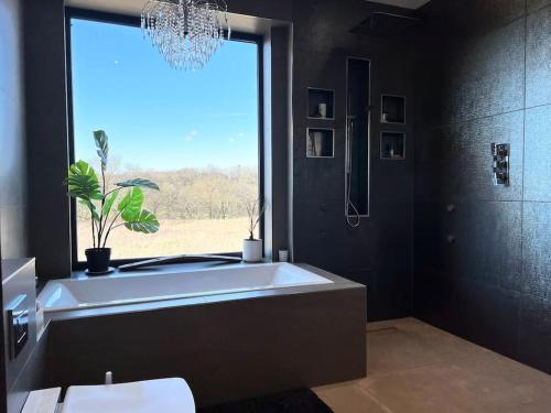 a bathroom with a large tub and a window at Manchester Luxury Country House Close To The City With Hot Tub & BBQ Fire Pit. in Manchester