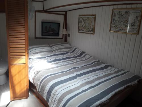 Ce lit se trouve dans une chambre dotée d'une couverture rayée. dans l'établissement Peniche Caroline, à Capestang