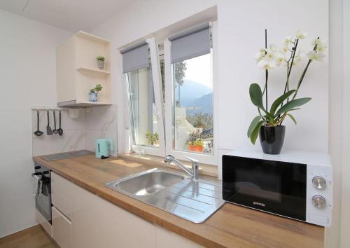 a kitchen with a sink and a microwave and a window at Studio Apartman Karlita in Slano
