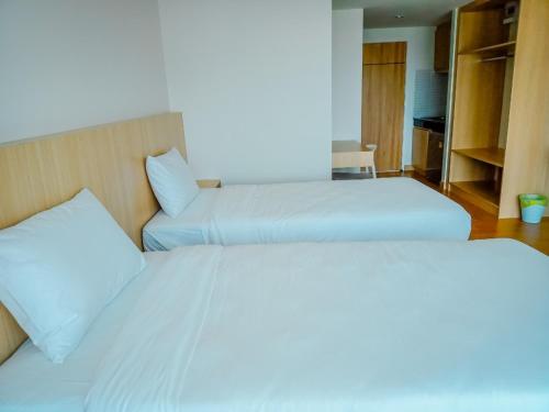 HATCHAO HERITAGE BEACH FRONT RESORT في Ban Hat Cha Samran: سريرين في غرفة الفندق ذات شراشف بيضاء