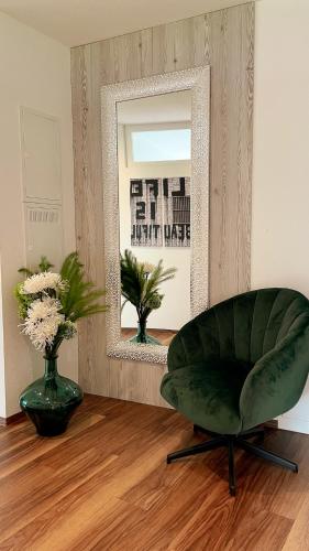 a green chair in a living room with a mirror at TheView Ahorn in Fügen