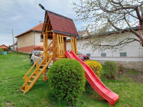 a wooden play house with a slide in a yard at Penzion MAYKA in Hrabušice