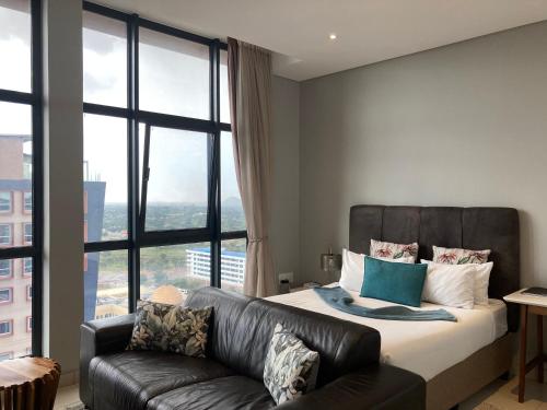 a bedroom with a bed and a leather couch at Urban Awe Apartment- iTowers 18th Floor in Gaborone