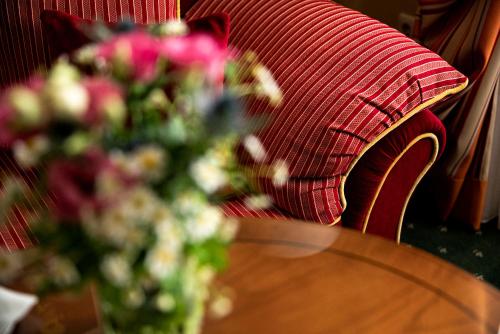 a red couch with a table and a vase of flowers at Boutique-Hotel Amalienhof in Weimar