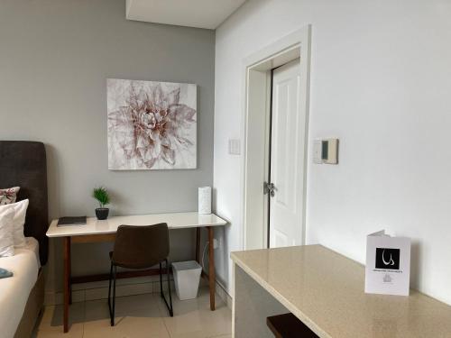 a white room with a desk and a bed and a table at Urban Awe Apartment- iTowers 18th Floor in Gaborone