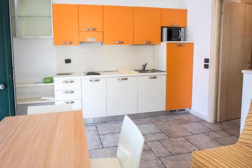 une cuisine avec des armoires orange, une table et des chaises dans l'établissement A08 - Poggio, delizioso bilocale al piano terra, à Poggio