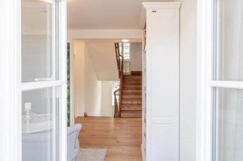 a hallway with white walls and wood floors and a staircase at Verena's Boutique Villa au lac in Sachseln