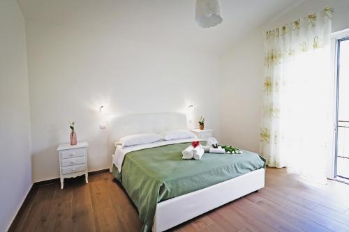 Acquasanta Relais في Laureana Cilento: غرفة نوم بيضاء مع سرير مع دمية دب عليها