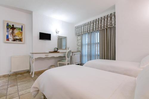 a hotel room with two beds and a television at Villa Fora Hotel in Alacati