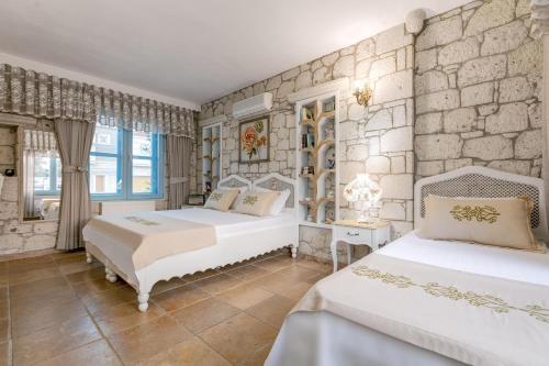 a bedroom with two beds and a stone wall at Villa Fora Hotel in Alacati