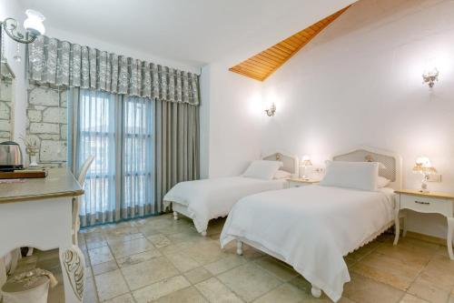 two beds in a room with white walls and windows at Villa Fora Hotel in Alacati