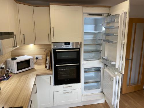 a kitchen with an empty refrigerator and a microwave at 'Sounion' - Fabulous, spacious modern house with large private garden in Leafy Lytham in Lytham St Annes