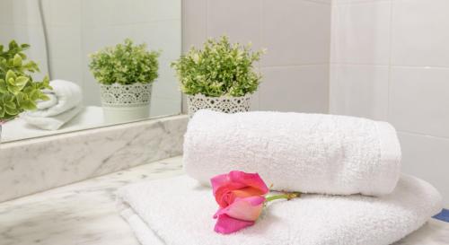 a pink rose sitting on a towel in a bathroom at Apartaments BT- ROSES in Roses