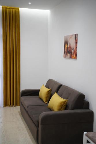 a black couch with two yellow pillows in a living room at Apartments Costa Azzurra in Velipojë