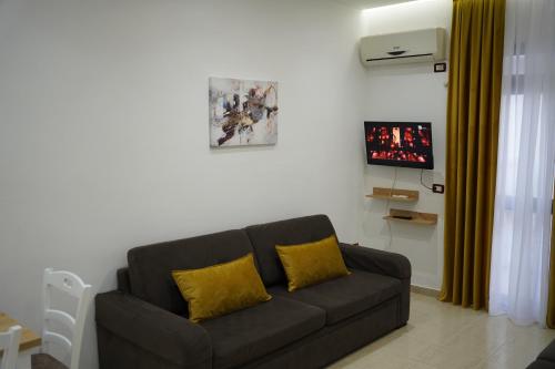 a living room with a black couch with yellow pillows at Apartments Costa Azzurra in Velipojë