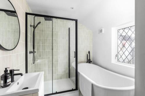 y baño con ducha, bañera y lavamanos. en Luxe Design - Chic Cottage - Heart of Rothbury en Rothbury