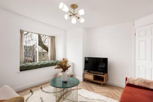 a living room with a couch and a television at Luxe Design - Chic Cottage - Heart of Rothbury in Rothbury
