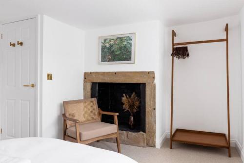 a living room with a fireplace and a chair at Luxe Design - Chic Cottage - Heart of Rothbury in Rothbury