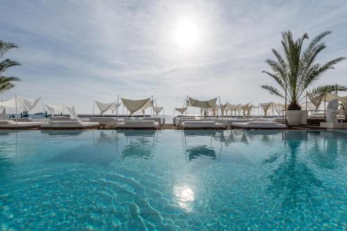 a large swimming pool with lounge chairs and palm trees at Vistamare Suite in Lido di Savio