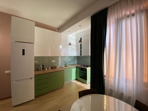 una cocina con armarios verdes y blancos y una mesa en Lovely and cozy apartment! en Kutaisi